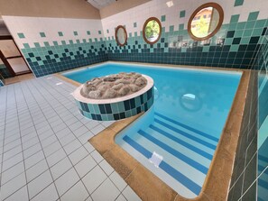 Ein Swimmingpool mit einem runden Whirlpool, gefliesten Wänden und einem gefliesten Boden.