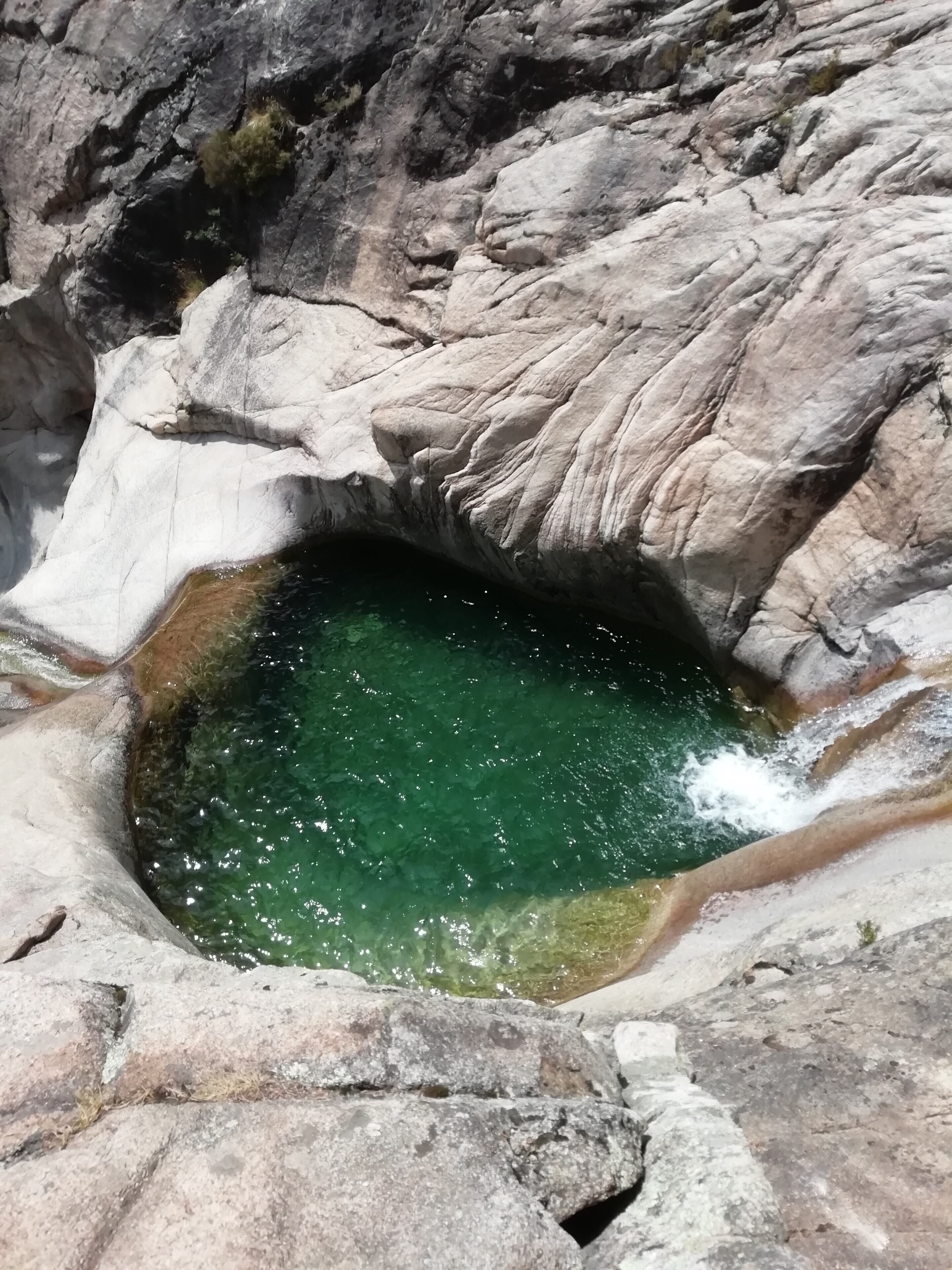 A natural rock formation with a clear water pool.