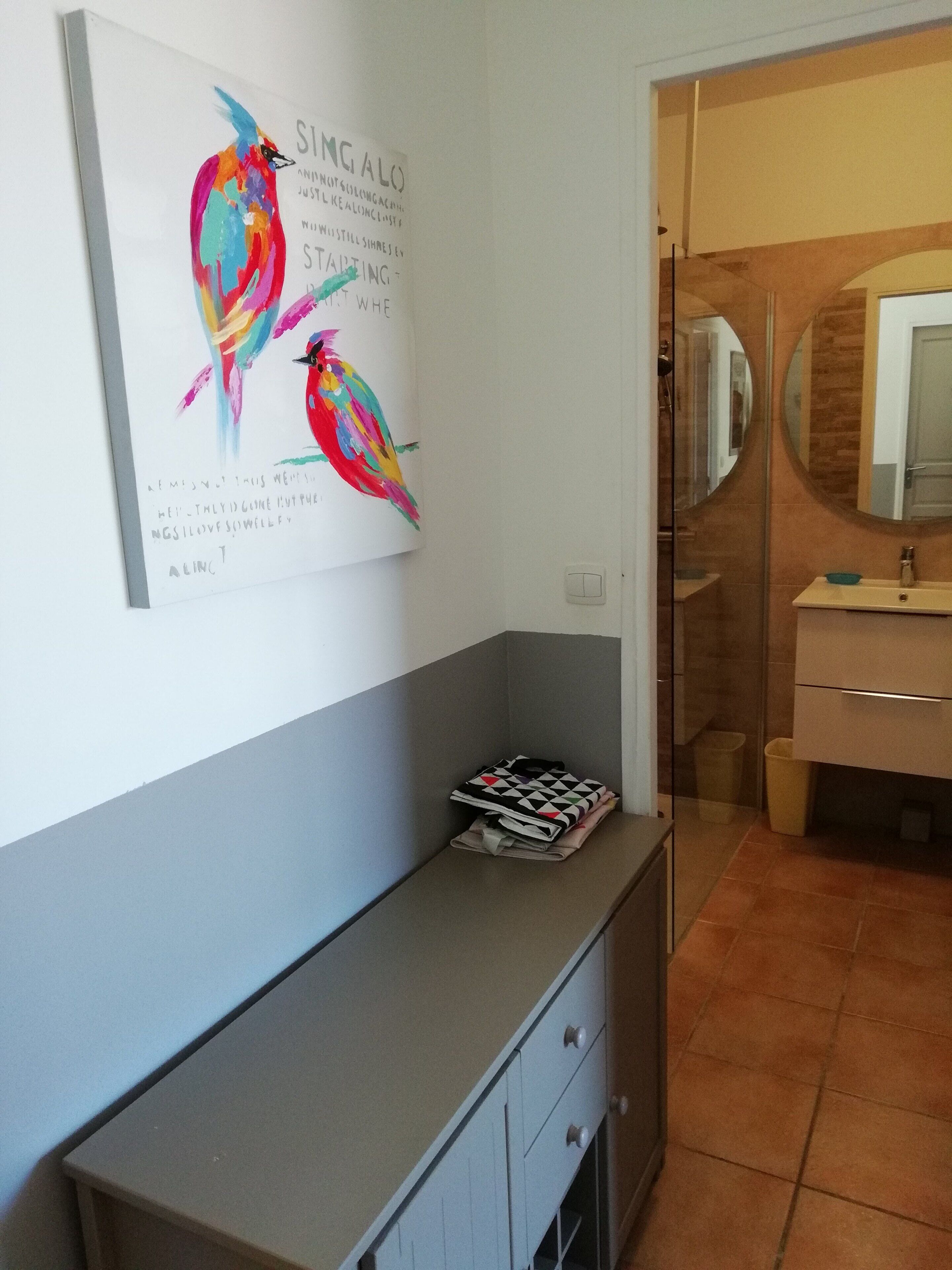 Une salle de bain avec un meuble-lavabo, un miroir et une œuvre d’art encadrée accrochée au mur.
