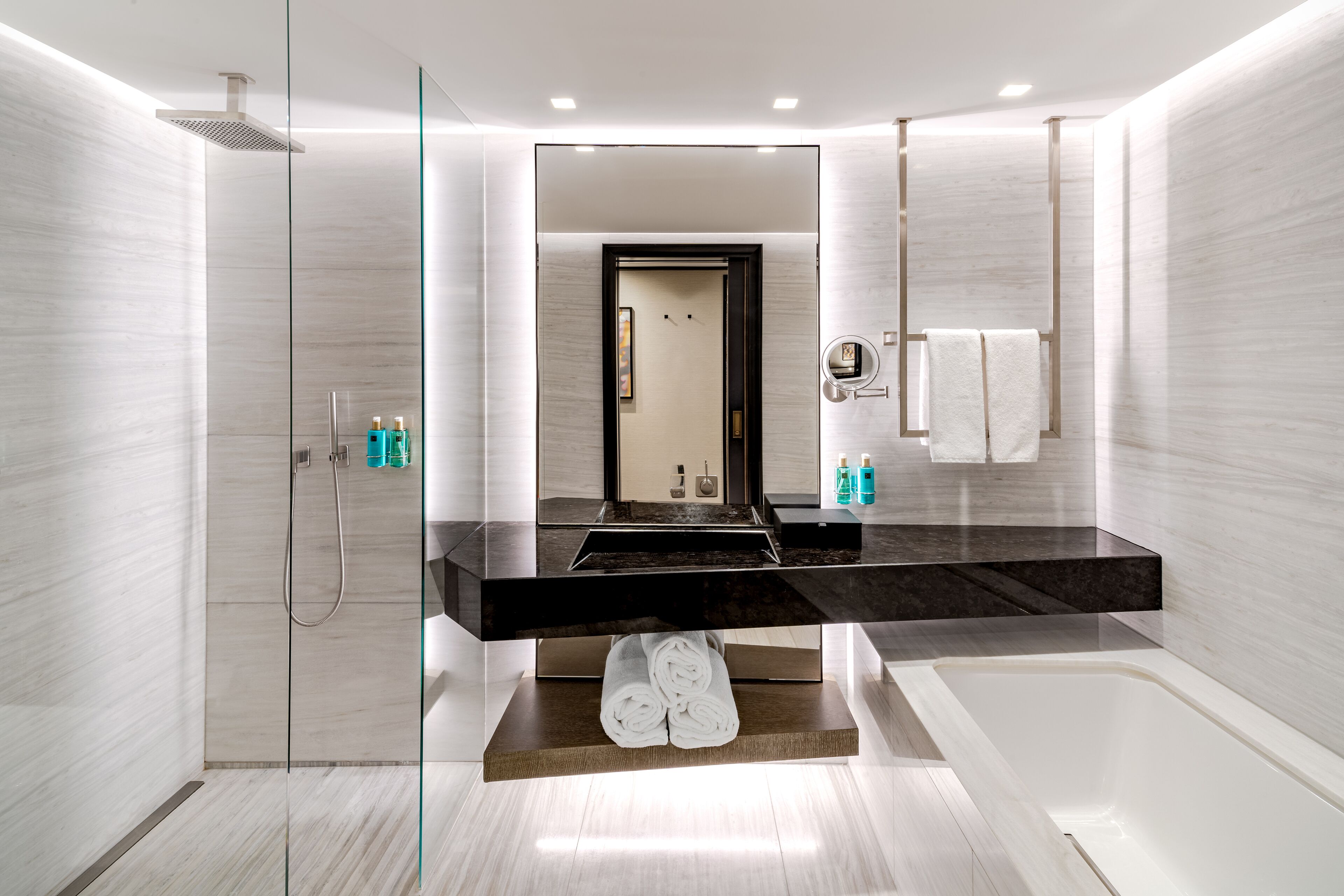A modern bathroom with a large mirror, a shower, and a bathtub.