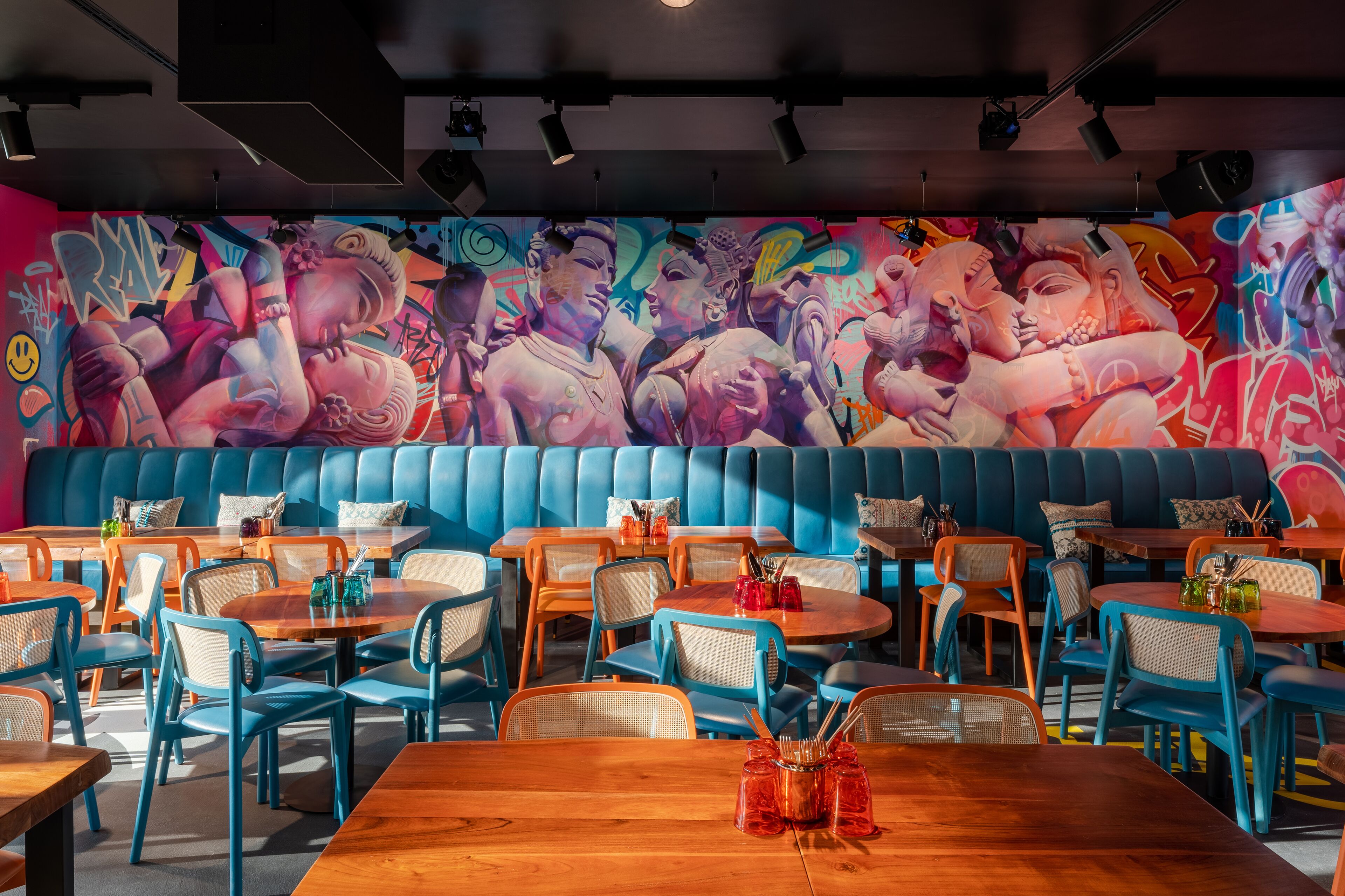 Un restaurant avec des banquettes bleues, des tables et des chaises en bois.