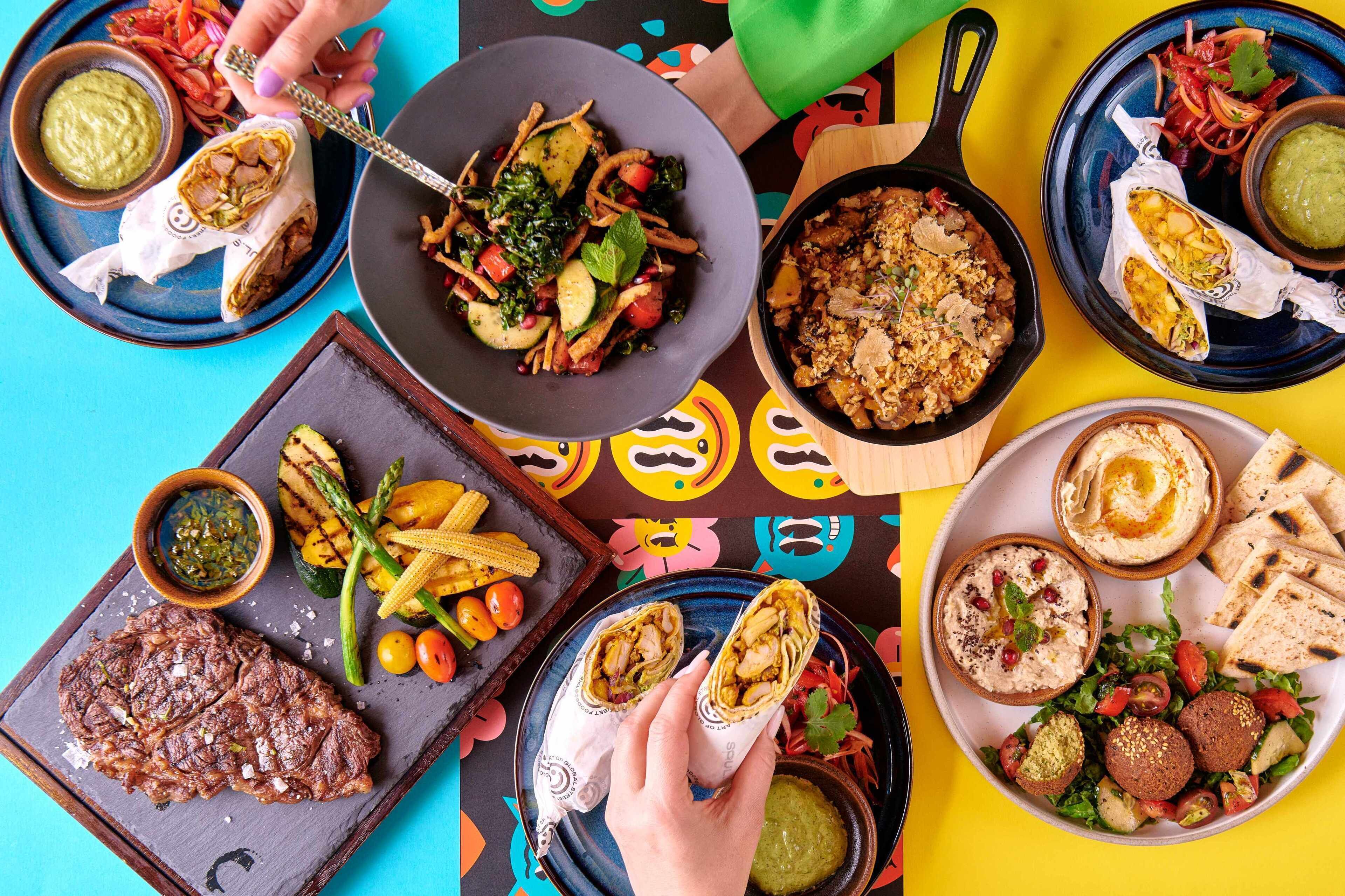 A variety of dishes including tacos, grilled vegetables, and a steak, suggesting a diverse dining selection.