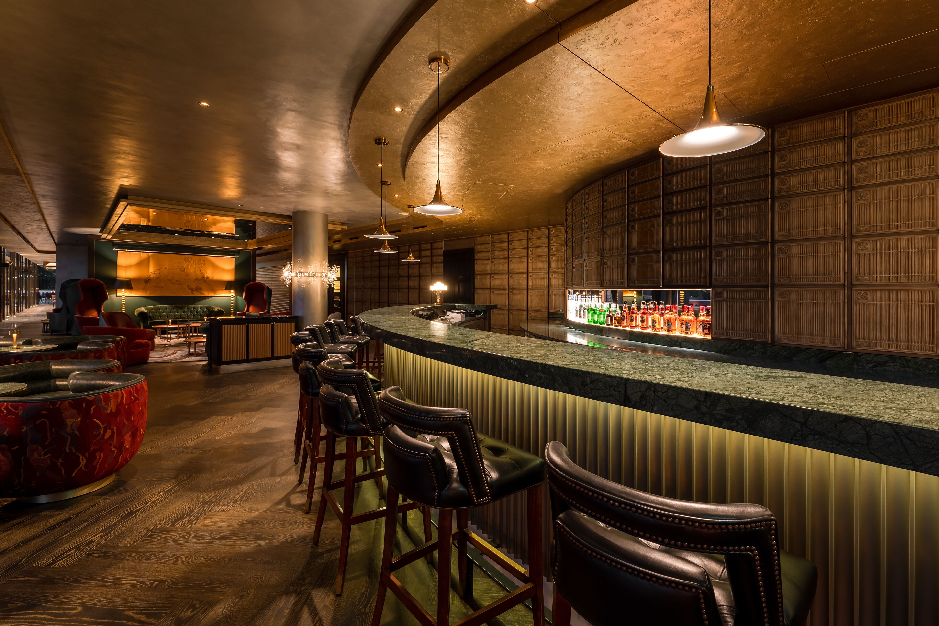 A bar area with a curved counter, leather bar stools, and a well-lit ambiance.