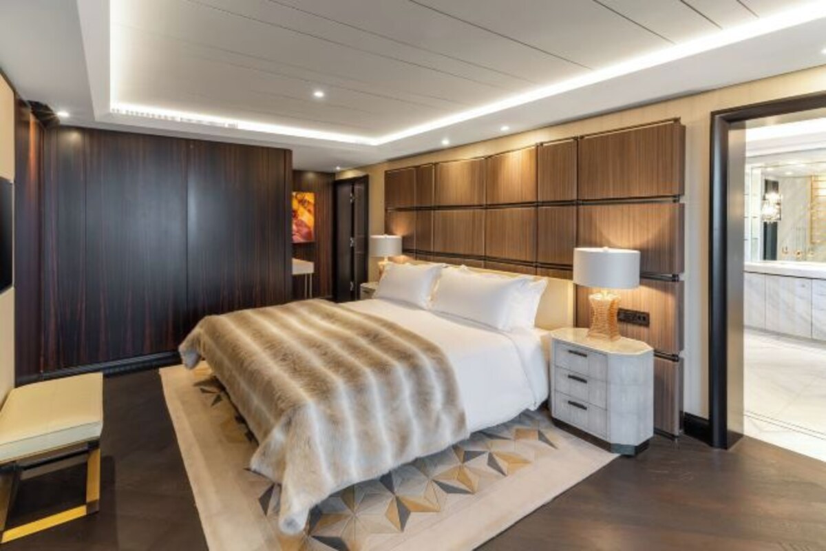 A modern hotel room with a large bed, bedside tables, a desk, and a view of the city.