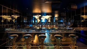 Eine Bar mit Weltkarten-Hintergrund, Barhocker und einer Auswahl an Flaschen.