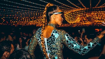 Una persona con un atuendo estampado en un evento concurrido, bajo un techo lleno de luces.