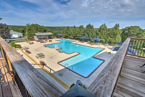 A pool area with multiple sections, lounge chairs, umbrellas, and a wooden deck.