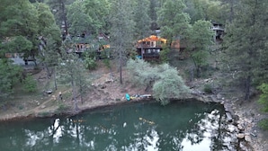 Järven rannalla sijaitseva mökki, jossa on useita kerroksia, ja sen ympärillä on tiheä metsä.