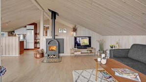 Un espace de vie chaleureux de style loft, doté d’un poêle à bois, d’une télévision et d’un coin salon confortable.