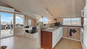 Une cuisine moderne avec des poutres en bois, un îlot central et une vue sur l’extérieur.