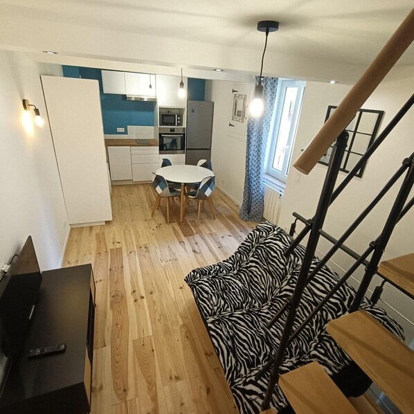 A compact living space with a kitchenette, dining area, and a zebra-patterned sofa.