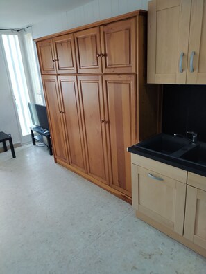 A kitchen with wooden cabinets, a black countertop, and a tiled floor.
