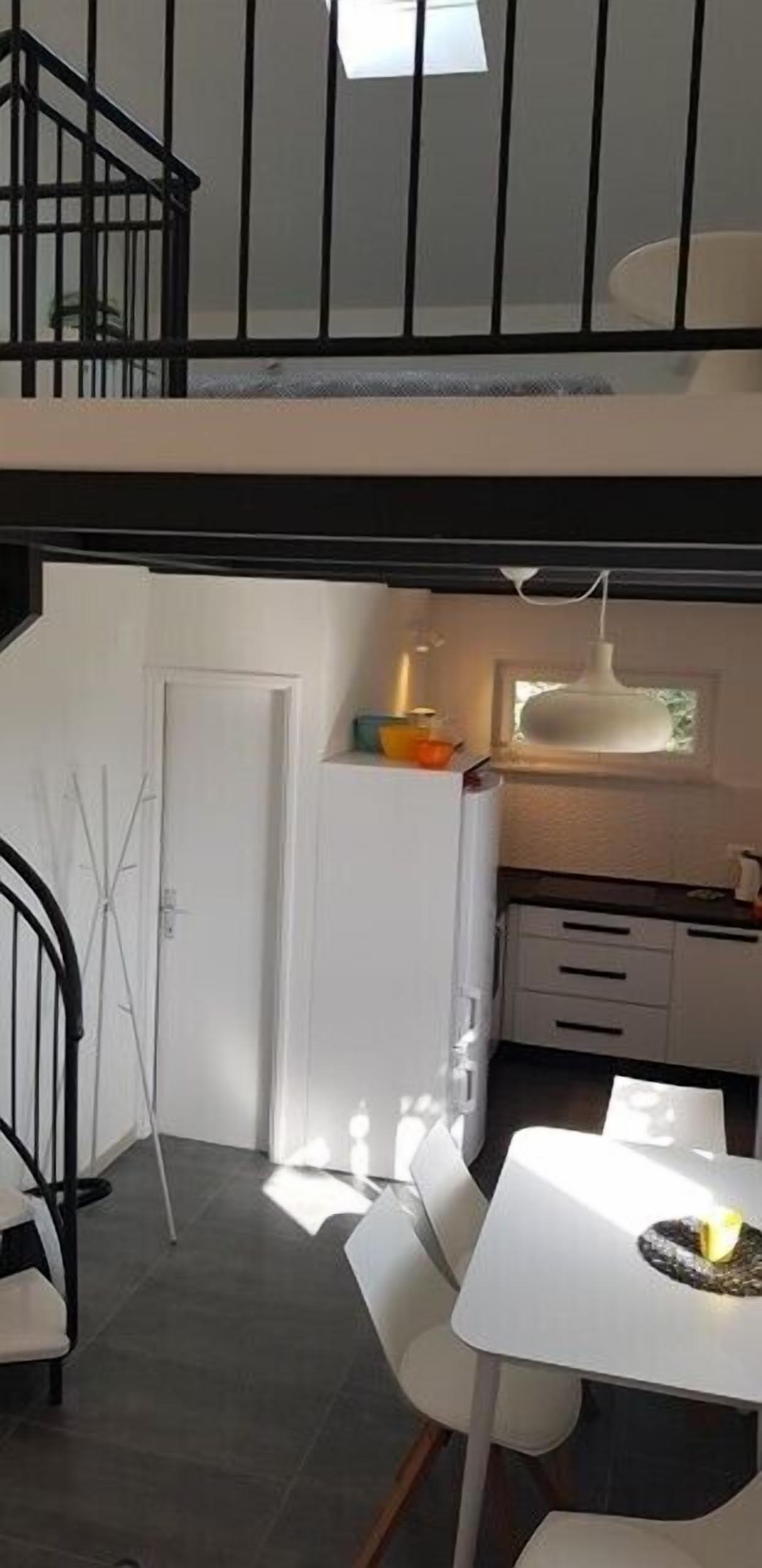 A modern kitchen with white cabinets, a dining table, and a staircase leading to an upper level.