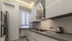 A modern kitchen with a gas stove, stainless steel appliances, and a window with white curtains. - GuestHost - Vatican museums cozy apt x6 (Roma)