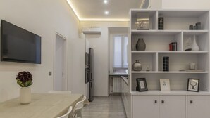 A modern kitchen with a dining area, white cabinetry, and a flat-screen TV mounted on the wall. - GuestHost - Vatican museums cozy apt x6 (Roma)