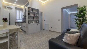 A modern kitchen with white cabinets, a dining table, and a built-in bookshelf. - GuestHost - Vatican museums cozy apt x6 (Roma)