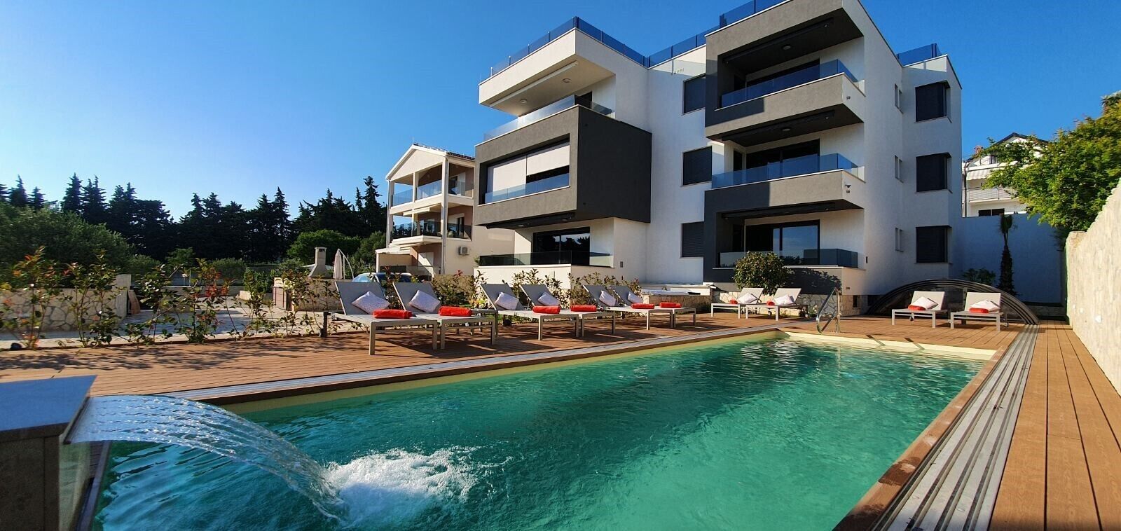 Un edificio moderno con piscina y tumbonas.