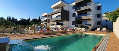 Un edificio moderno con piscina y tumbonas.