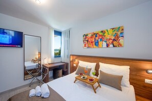 Une chambre d’hôtel avec un lit, un bureau, une chaise, une télévision et un tableau.