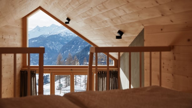 A wooden interior with a large window offering a view of snow-covered mountains.