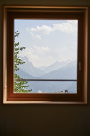A framed window with a view of mountains and a lake.