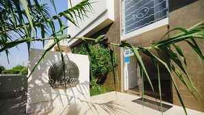 Un immeuble moderne avec une enseigne indiquant « Appartements Via del Faro » et une entrée en verre transparent.