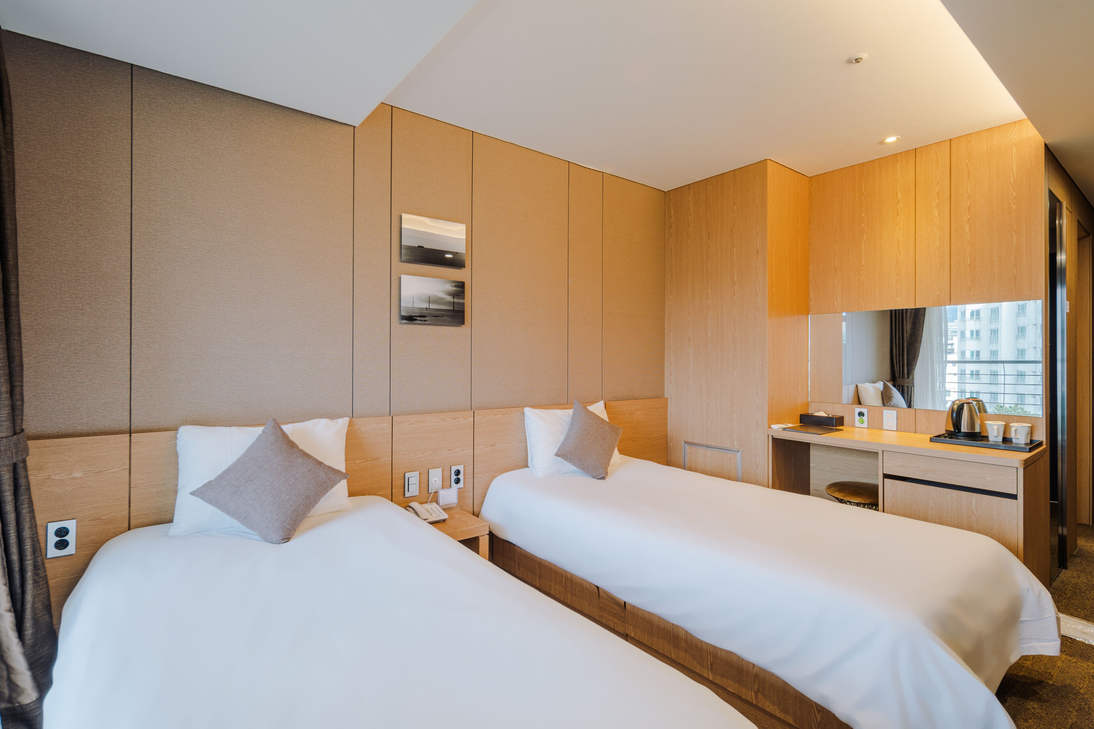 Une chambre d’hôtel avec deux lits, un bureau et un miroir.
