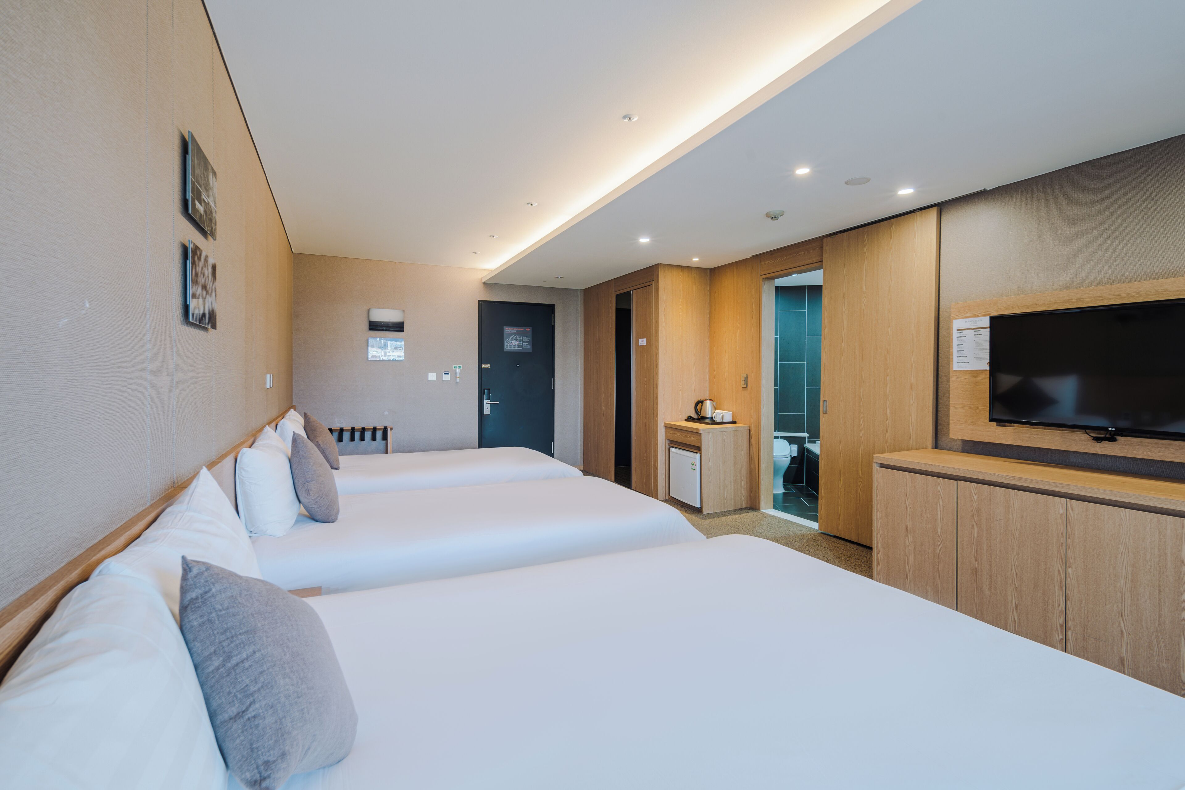 Een hotelkamer met twee bedden, een televisie, een bureau en een kleine kitchenette.