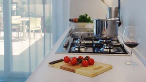 Une cuisine moderne avec une cuisinière à gaz, une planche à découper ornée de tomates cerises et un verre à vin.
