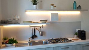 Une cuisine moderne équipée d’une cuisinière à gaz, d’un évier en acier inoxydable et d’ustensiles de cuisine suspendus.