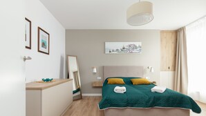 A modern bedroom with a bed, bedside tables, a mirror, and artwork on the walls.