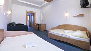 A hotel room with two beds, a desk, a chair, and a television. - Penzión DRUŽBA Bojnice (Bojnice)