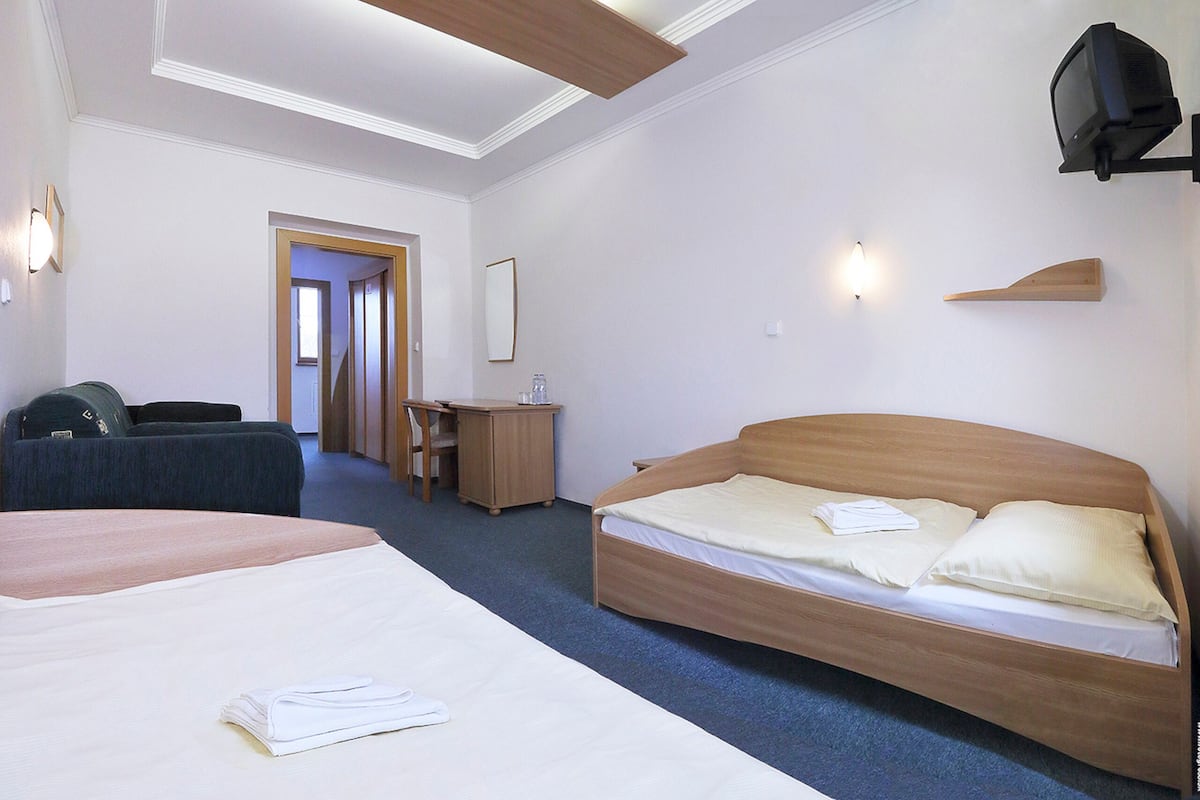 A hotel room with two beds, a desk, a chair, and a television.