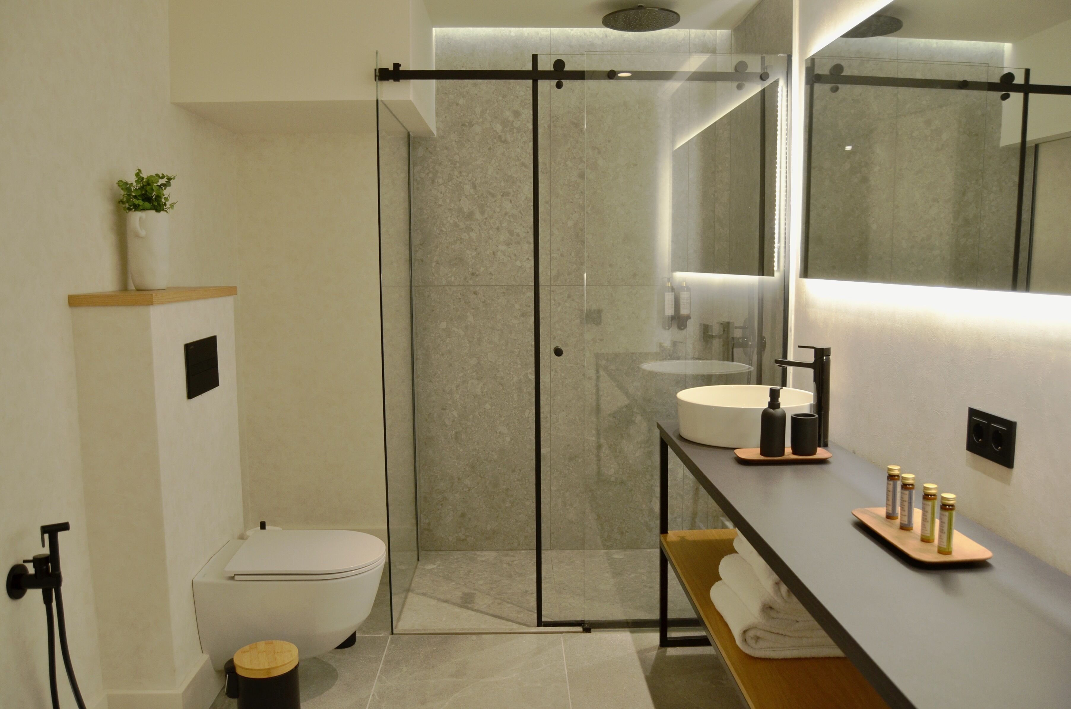 Un baño moderno con ducha de vidrio, inodoro y tocador con lavabo y espacio de almacenamiento.