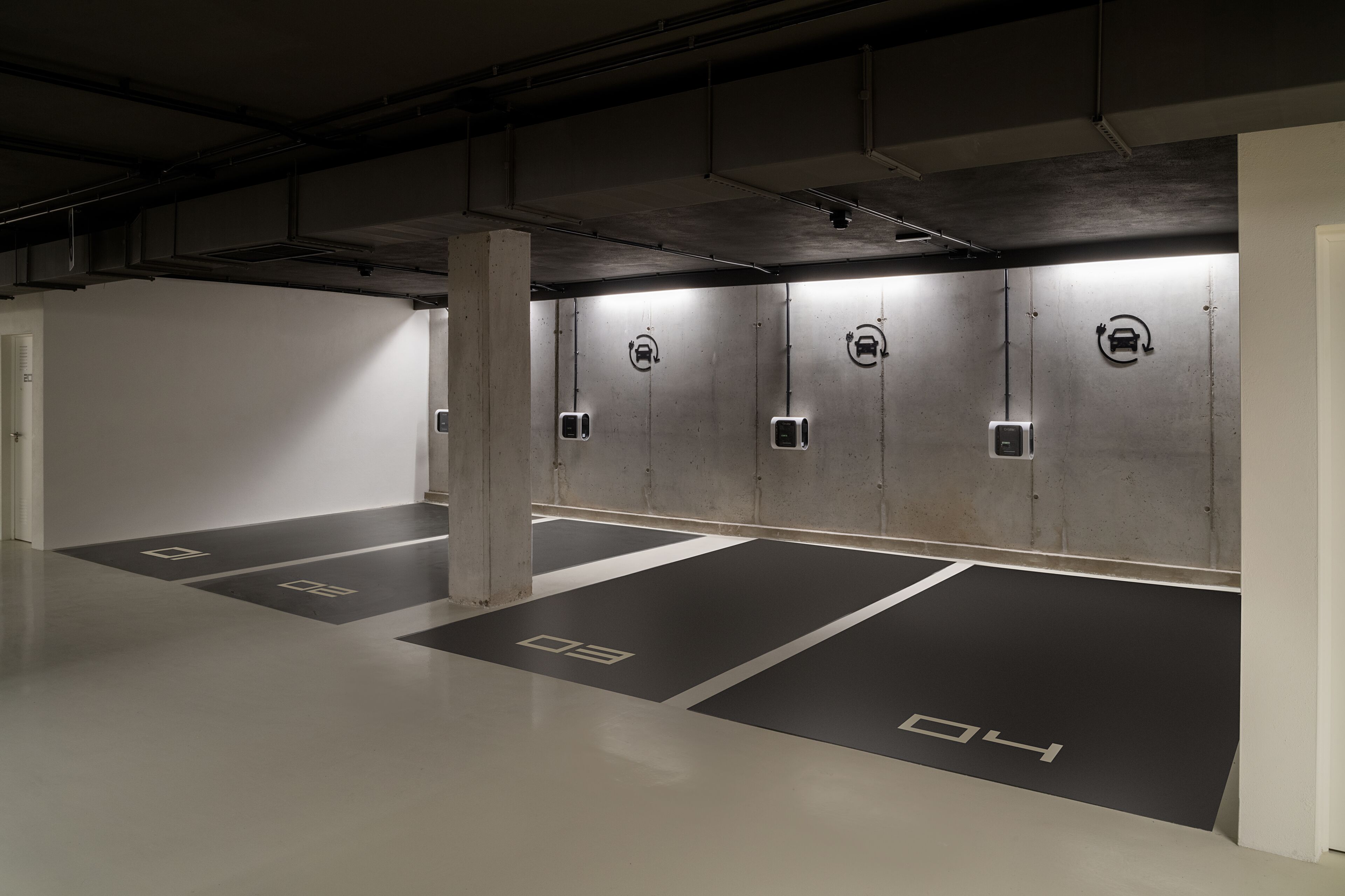 Eine Parkgarage mit Betonpfeilern, nummerierten Stellplätzen und beleuchteten Wänden.