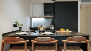 Une cuisine moderne dotée d’un îlot central, de trois chaises en bois et d’une table à manger dressée pour quatre personnes.