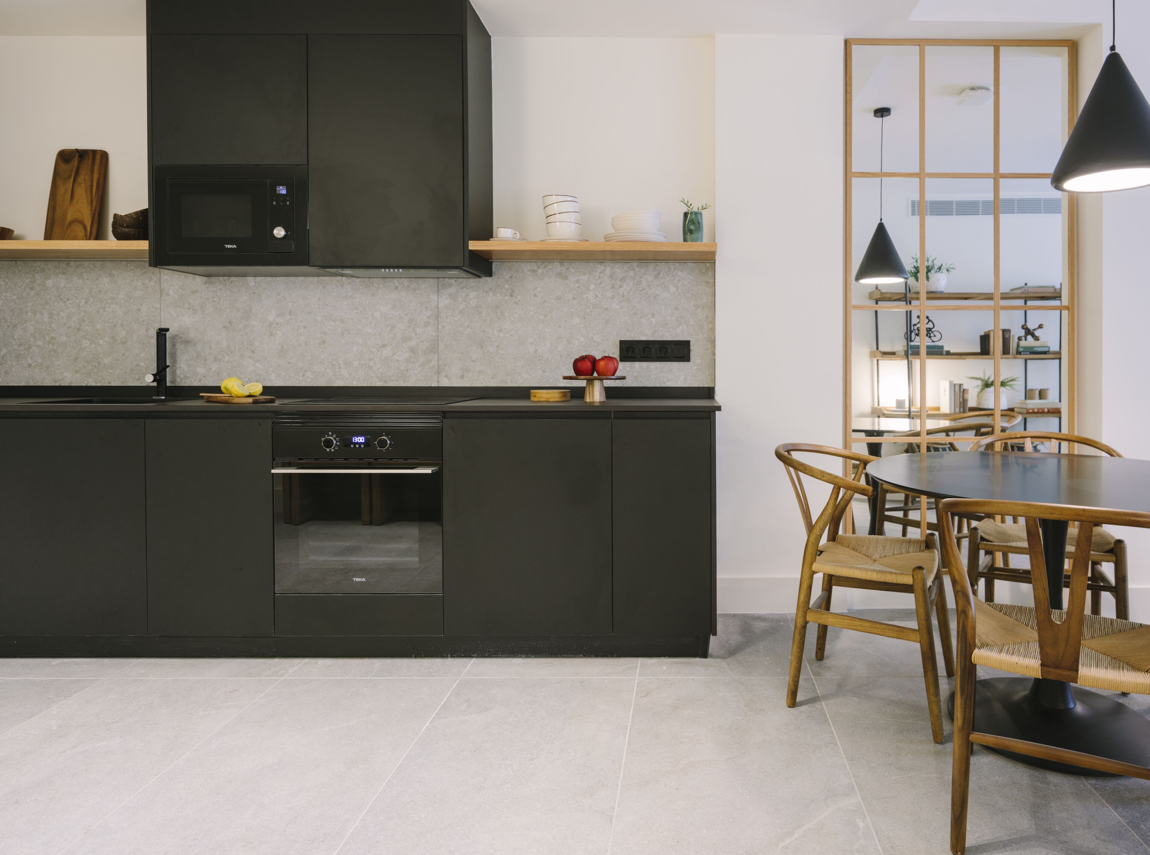 Uma cozinha moderna com forno embutido, micro-ondas e área de refeições com mesa redonda e cadeiras.