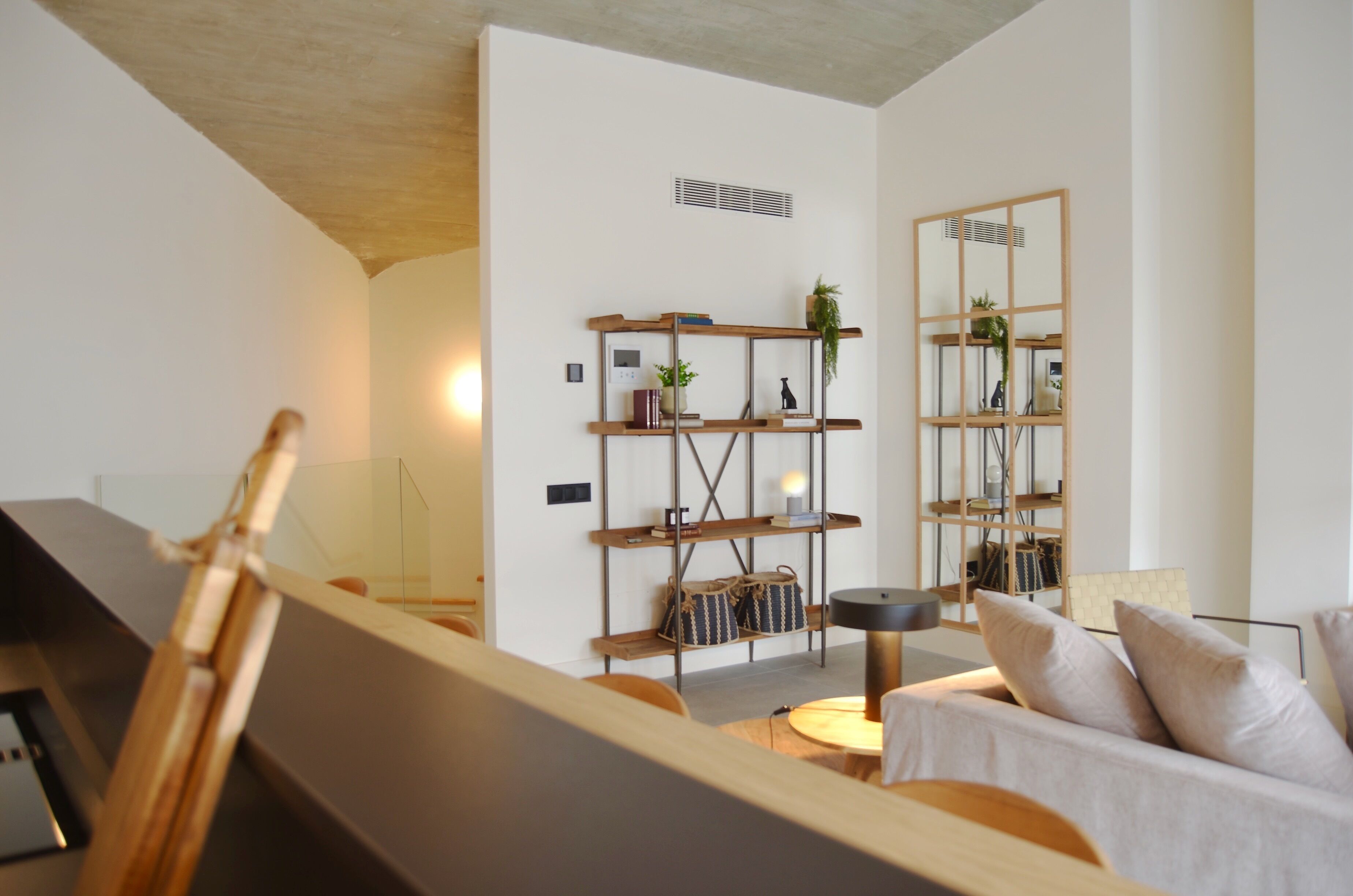 Un salon moderne avec une table basse en bois, un canapé agrémenté de coussins et une bibliothèque décorative.