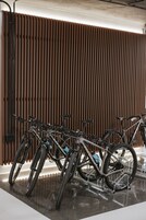 A bike rack with multiple bicycles parked against a wooden slat wall.