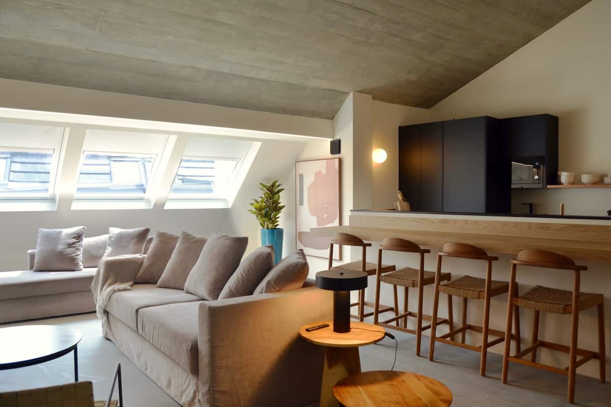 Un salon moderne comprenant un canapé, une table basse et un coin bar avec des tabourets.