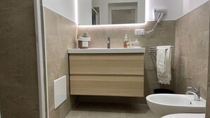 Un baño moderno con un espejo grande, dos lavamanos, un perchero y un cabezal de ducha.