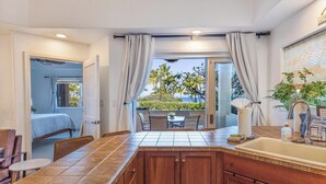Une cuisine moderne dotée d’un grand îlot central, d’un coin repas et offrant une vue sur l’extérieur.