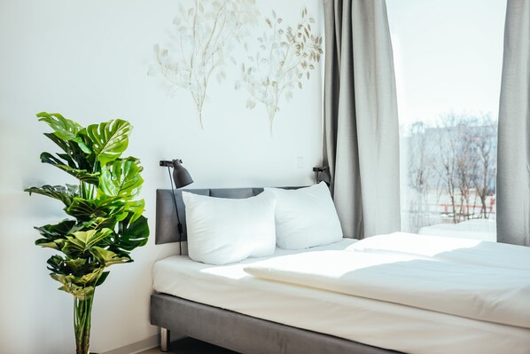 A modern bedroom with a large bed, a potted plant, and a wall art piece. - The Rix Studio near SBahn Neukölln (Berlin)