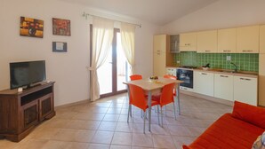 A compact living space with a dining area, kitchen, and a TV on a wooden cabinet. - Villa con Piscina - BUDONI (San Lorenzo)