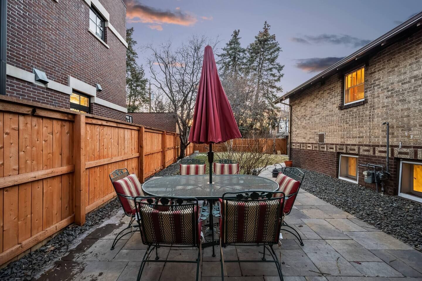 A patio with a round table, chairs, and a red umbrella.