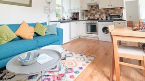 Ein modernes Wohnzimmer mit einem blauen Sofa, einem kleinen runden Tisch und einem farbenfrohen Teppich.