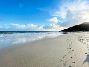 A beach with footprints, calm water, and a clear sky.