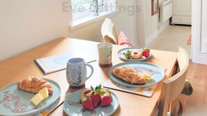 Ein Frühstückstisch mit Croissants, Erdbeeren und einer Tasse.