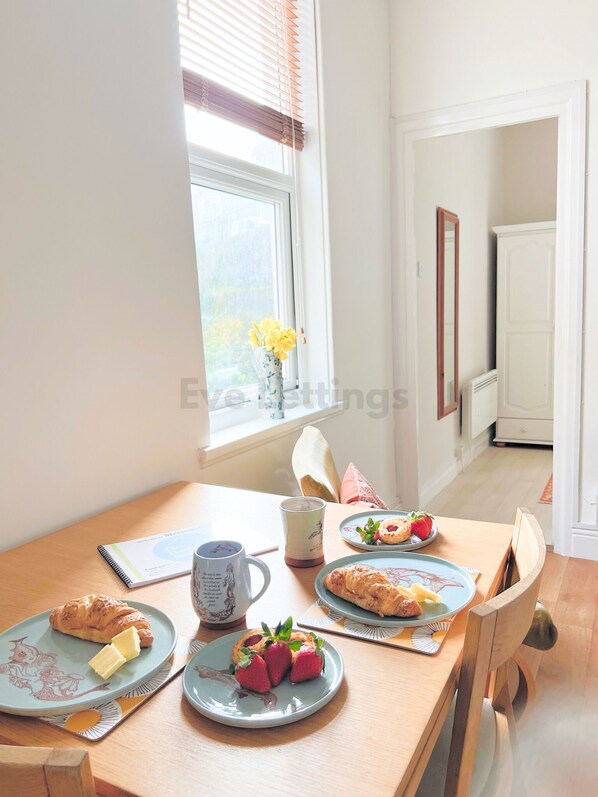 A breakfast table with croissants, strawberries, and a mug.