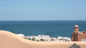 A coastal town with white buildings and a sandy foreground. - House (Bahía de Casares)